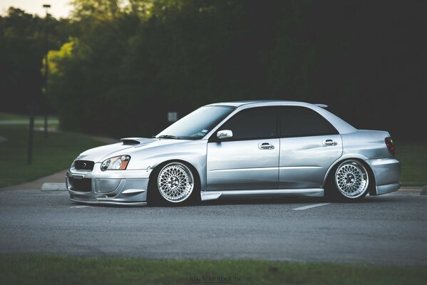 Silver Subaru on a background of trees
