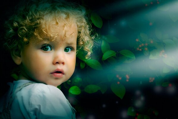 Blonde baby on a background of green petals