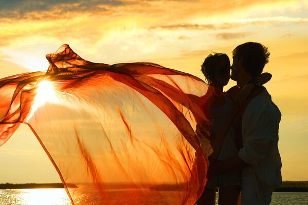 A couple embraces against the backdrop of a sunset on the lake
