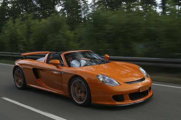 A convertible in motion on the road against the background of the forest
