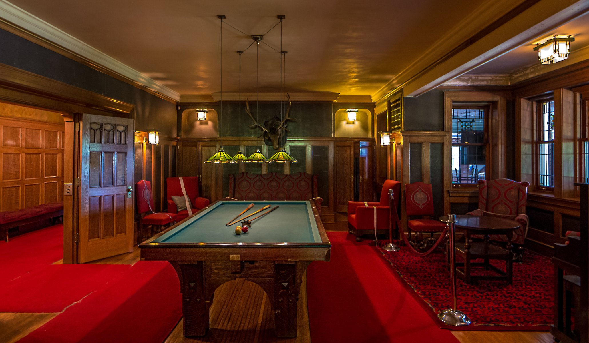 pool chandelier red carpet moose head chair table window light