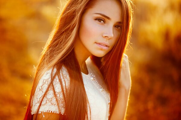 Red hair of a girl against the background of sunlight