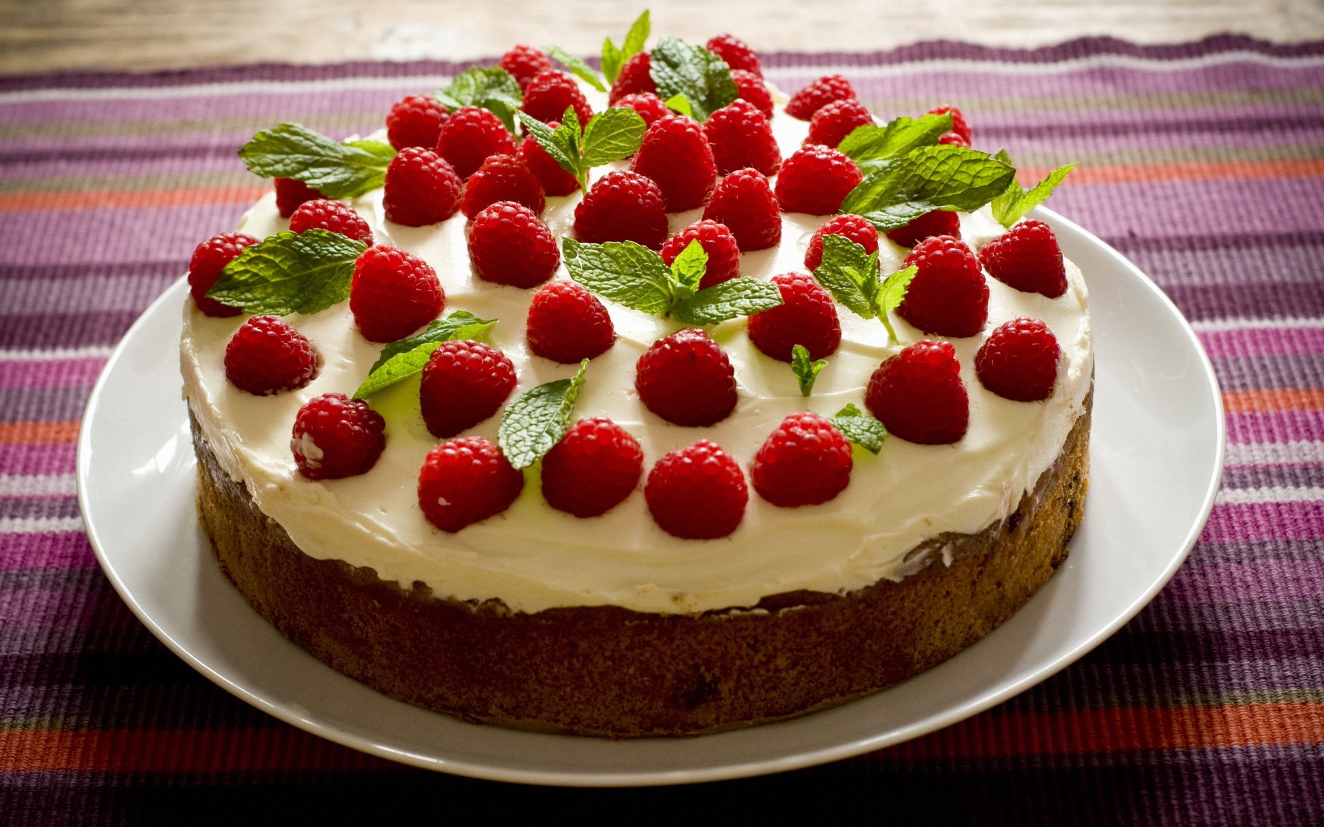 food sweet cake sponge cake cream cream leaves greens leaves raspberries red green brown plate tablecloth