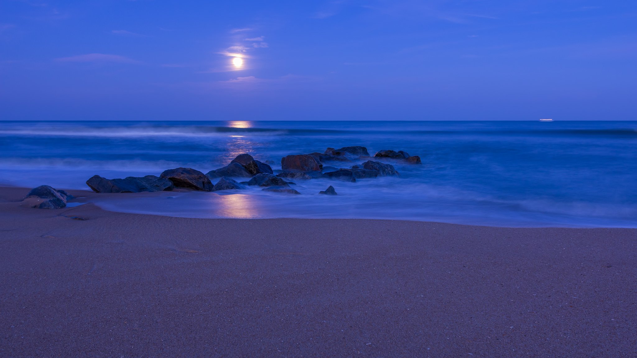 ocean shore beach sand rocks night blue sky clouds moon